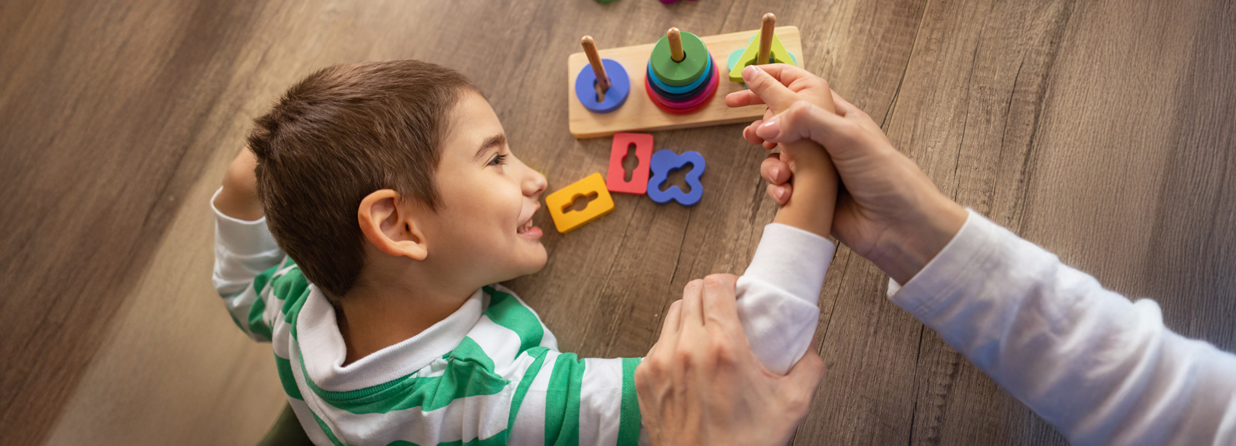 A dedicated female nurse supports a young autistic boy using sensory toys to enhance motor abilities.